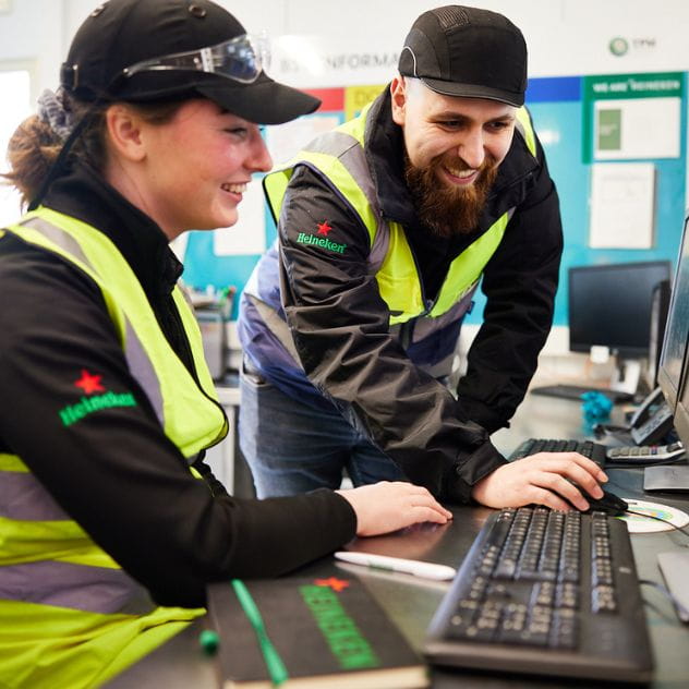 Colleagues working on computer in brewery.