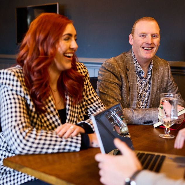 Two colleagues smiling and laughing at table in bar